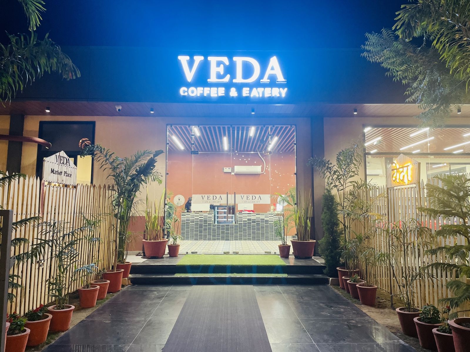 The illuminated entrance of Veda Coffee & Eatery at night