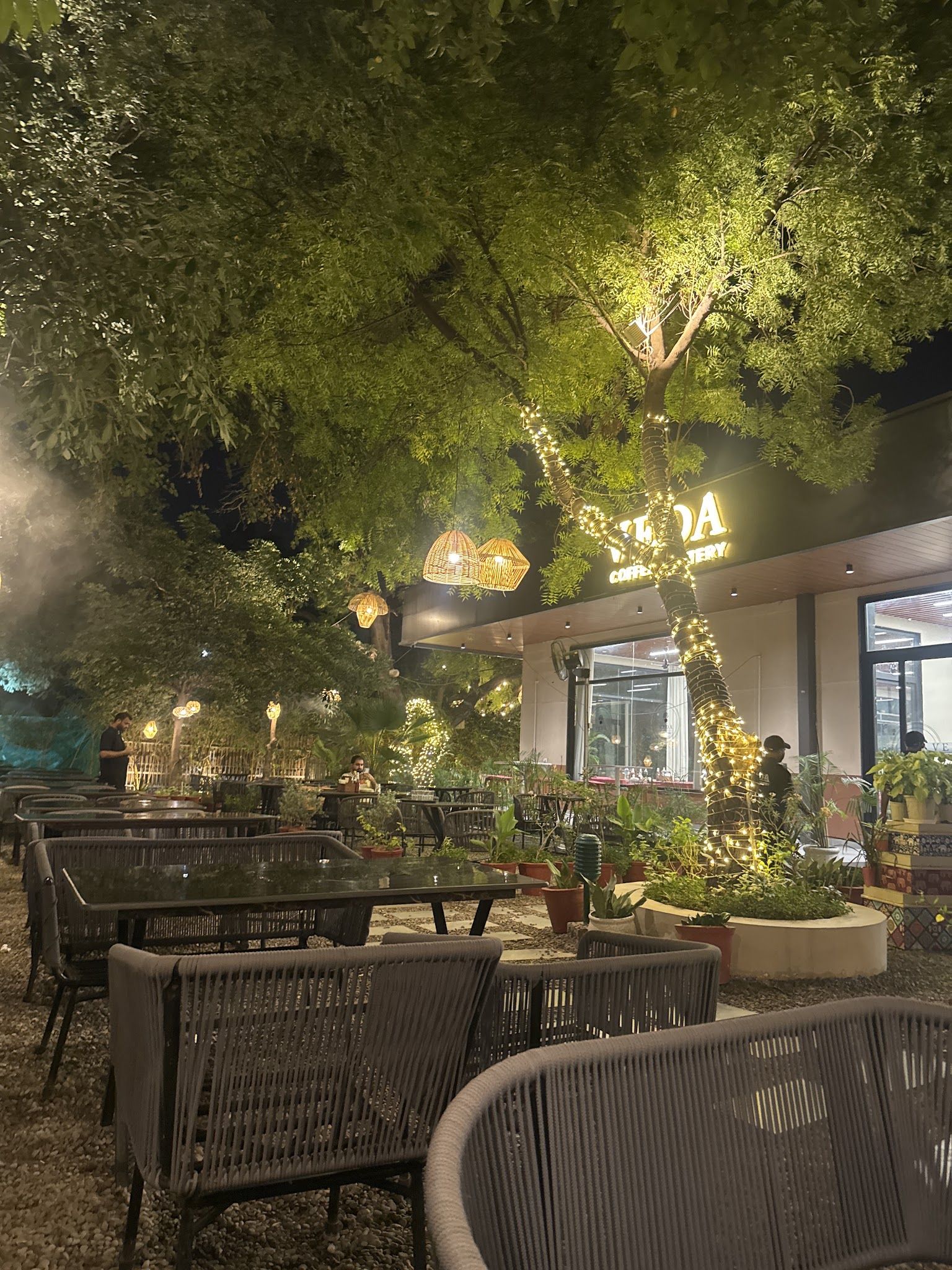 The garden seating at night with the lit café behind