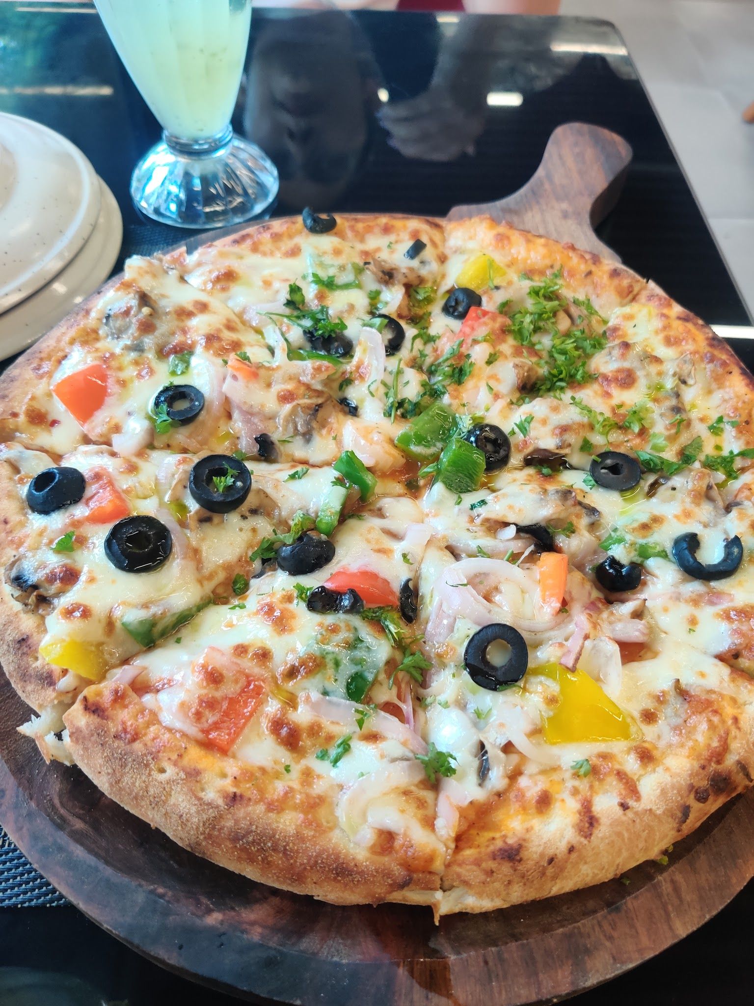 A wood-fired pizza with olives, peppers, onion and mushroom