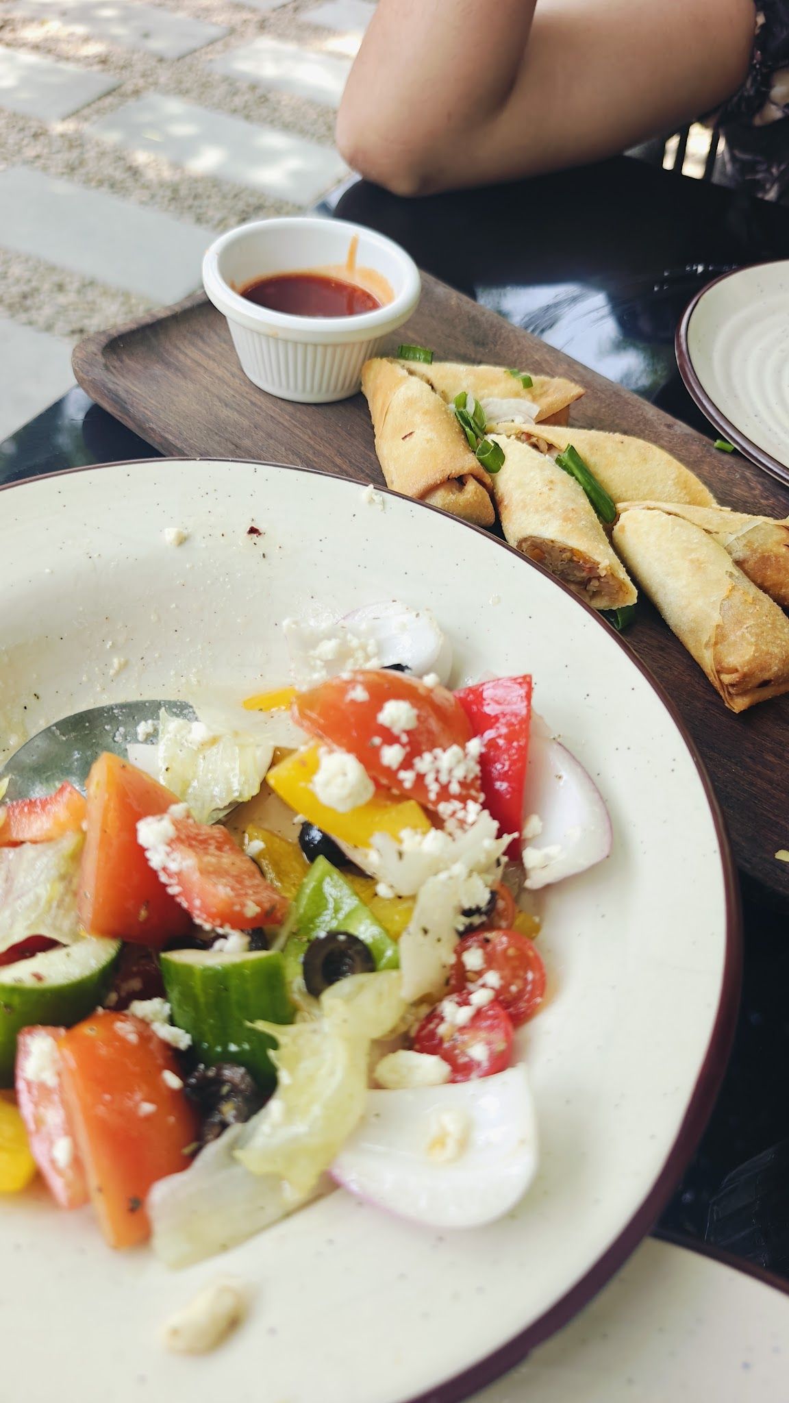 A feta salad and spring rolls on a wooden tray