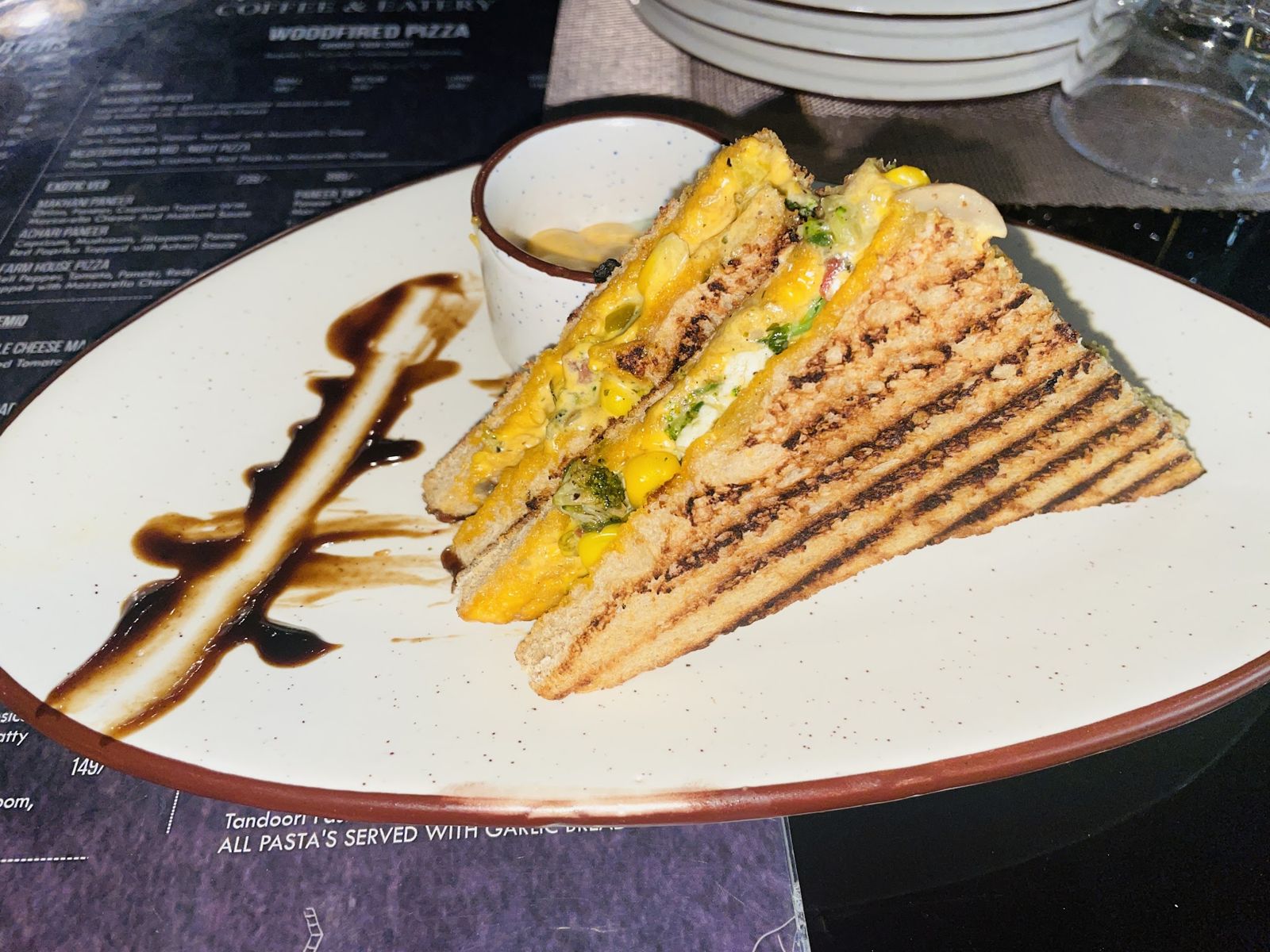 A grilled sandwich cut into triangles with a dip