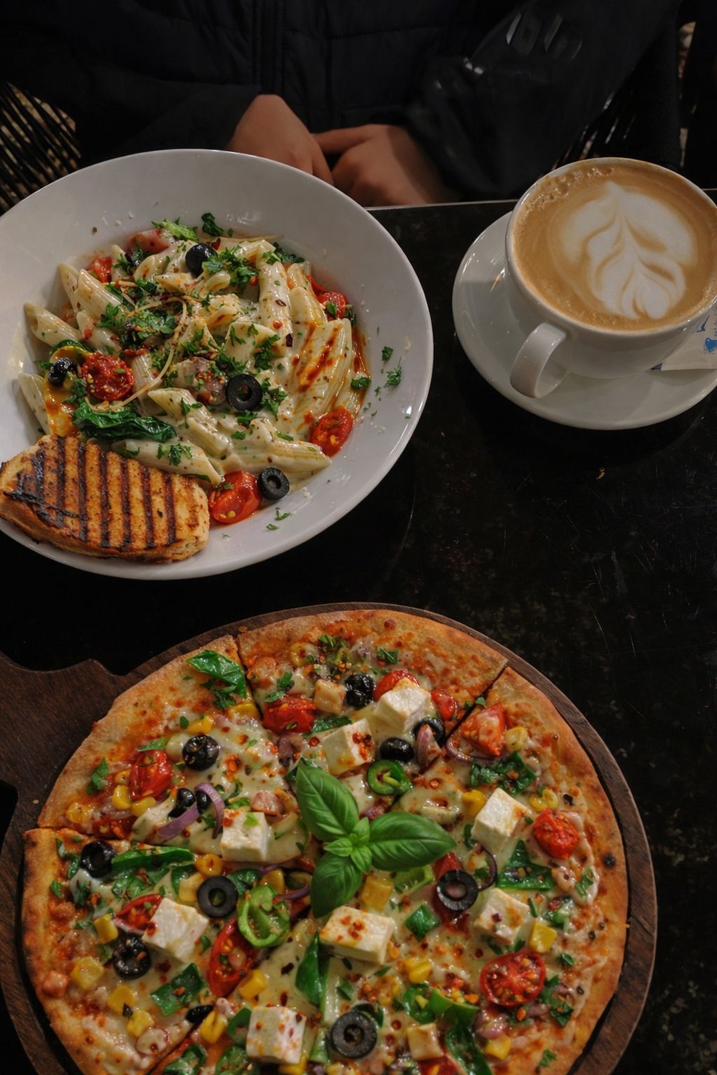 Pasta, a vegetable pizza and coffee on a table, seen from above